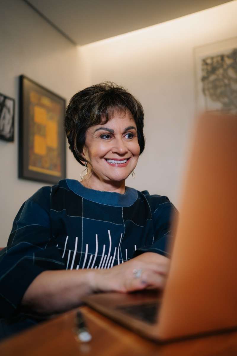 Dra. Regina Celi realizando atendimento online pelo notebook